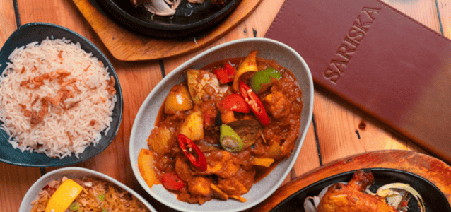 Warm Indian restaurant in Alderley Edge with diners enjoying curry and naan while a live jazz duo performs at night